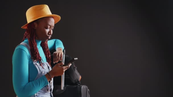 現代のモデルは 休日の目的地に出発する前にスマートフォン テキストメッセージをチェック 若い女性は携帯電話でソーシャルメディアを閲覧し 旅に出る準備をしています 手持ち撮影 — ストック動画