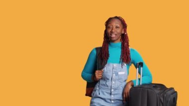 Gülümseyen kişi evet diyor. Stüdyoda kabul ve onay sembolü gösteriyor. Bagajı olan genç gezgin pozitif ve iyimser, kamerada destek gösteriyor..