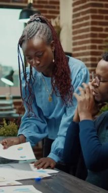 Dikey video: İş ortakları veri raporlarını inceliyor, çalışanlar yeni gelişim vizyonunu açıklamak için telefonla konuşuyor. Erkek işçi toplantı odasındaki müdürle konuşmak için cep telefonu hattını kullanıyor.