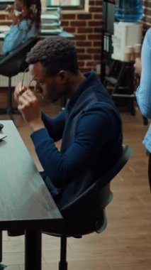 Dikey video: İş ofisindeki yıllık verileri inceleyen başlangıç analisti, araştırma projesi oluşturmadan önce kurumsal belgeleri gözden geçiriyor. Birlikte çalışma alanında istatistiklerle çalışan erkek çalışan.