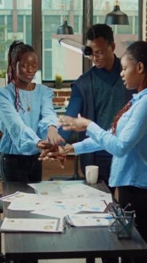 Dikey video: Gülümseyen iş arkadaşları başarının keyfini çıkarırken, iş geliştirme ve artan kâr elde ettikten sonra el ele tutuşup tezahürat yapıyorlar. Neşeli insanlar şirket istatistiklerinden mutlu olurlar.