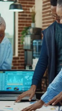 Dikey video: İş ekibi başlangıç sonuçlarını inceliyor, ortak çalışma alanındaki karı artırmak için işbirliği üzerinde çalışıyor. Yönetim kurulundaki ofis çalışanları yıllık şirket raporu ve geliştirme planlıyorlar..