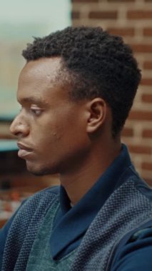 Dikey video: İş ortaklığında dizüstü bilgisayarla çalışan Afrikalı Amerikalı adam, geliştirme stratejisi istatistiklerini kontrol ediyor. Genç yönetici, kazanç ve uzmanlığı artırmak için verileri açıklıyor