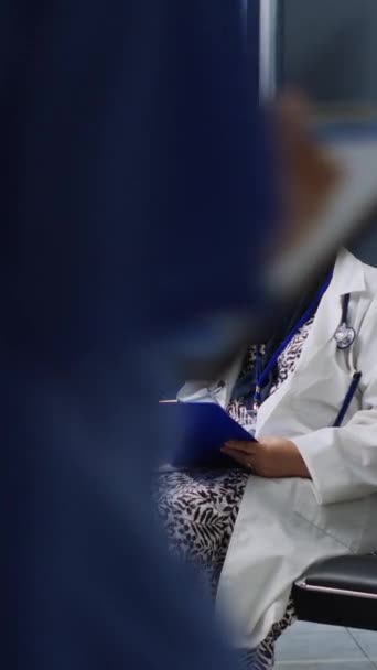 Вертикальное Видео Врач Помогает Пациенту Заполнить Медицинские Карты Время Осмотра — стоковое видео