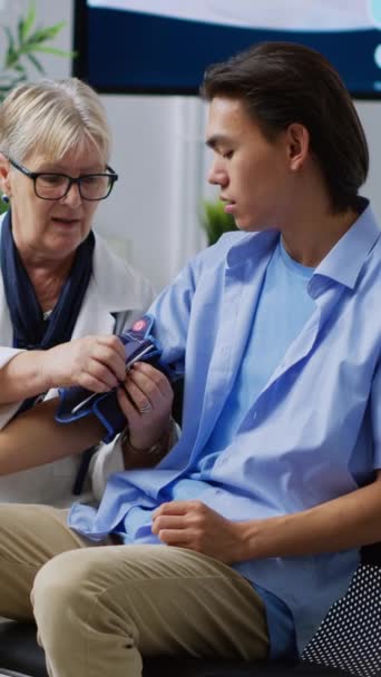 Vertikal Video Senior Traumatolog Som Bruker Tonometer Sjekke Pasientenes Høye – stockvideo