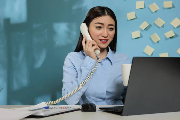 Asyalı Kadın Telefonda Konuşuyor Ofisteki Yerinde Otururken Gülümsüyor Adamı Laptopta — Stok fotoğraf