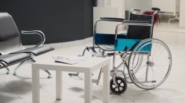 Hastane lobisinde boş tekerlekli sandalye, sağlık hizmetleri broşürleri ve kayıt formlarıyla dolu teşhis merkezi. Resepsiyonda resepsiyon, maluliyet dostu klinik tesisi.