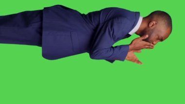 Dikey video: Modern bir çalışanın stüdyoya hava öpücüğü gönderip romantik jestler yapması, kamerada iyimser ve pozitif hissetmesi. Genç yetişkin yeşil perde arkaplanı üzerinde öpüşüyor.