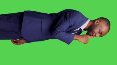 Dikey video: Afrikalı Amerikalı iş adamının stüdyoda sus işareti göstermesi, gizli kişinin sır ve mahremiyet için sessiz jest yapması. Erkek girişimi çalışanı gizliliği bozuyor
