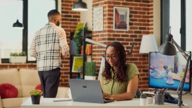 Evden uzakta çalışan Afrikalı Amerikalı bir kadın, muhasebe satış raporlarını planlamak için internet bilgilerini analiz ediyor. E- posta göndermek için internetteki finansal verileri kullanmak, şirket işi.