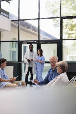 Doktor, hastane bekleme alanındaki muayene sırasında kıdemli hastaya tıbbi uzmanlığı açıklıyor. İhtiyarın muayeneden önce sigorta belgesini imzalaması. Sağlık hizmetleri