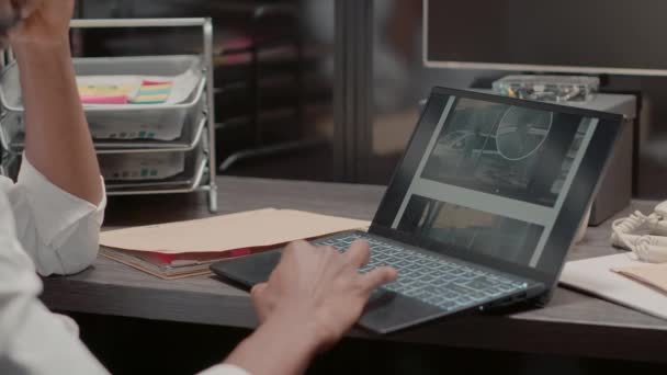 警察官はノートパソコンで犯罪事件のファイルを調べ壁に証拠地図を貼って机に座ってる インシデントルームで容疑者を捕まえるために監視カメラの映像を調べる私立探偵 — ストック動画