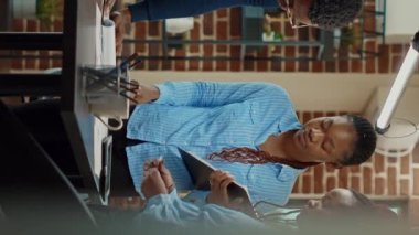 Dikey video: Başlangıç ekibi toplantı salonunda veri okuyor, kârı artırmak için resmi belgelere bakıyor. İş arkadaşları yeni gelişim çözümleri buluyor, iş yerlerindeki kağıtları kullanıyorlar