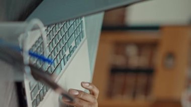 Dikey video: Şirket yöneticisi sunum yapmak için dizüstü bilgisayar kullanarak rapor ve bilgi içeren belgeler okuyor. Yıllık veri istatistiklerini inceleyerek iş çözümleri bulmaya çalışan erkek çalışanlar