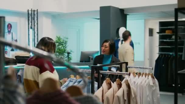 年轻人在商店里谈论时尚系列 顾客和员工在精品店里看时髦的新衣服 两名妇女在购物中心分析零售店商品 — 图库视频影像