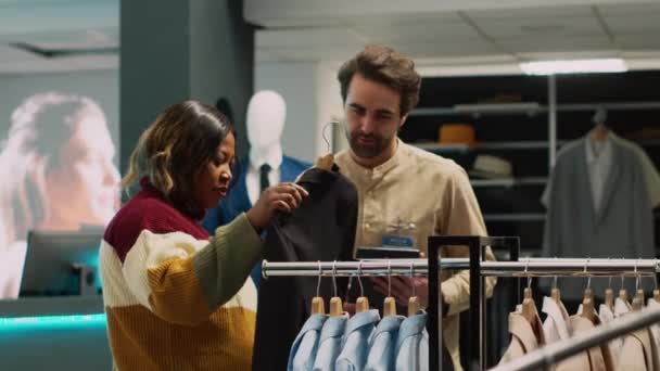 Розничный Работник Помогает Клиенту Выбрать Современную Одежду Женщина Ищет Модные — стоковое видео