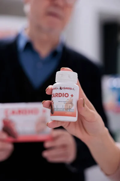 医療従事者と高齢者の心臓のサプリメントの違いを議論し 2つの薬箱を保持 薬の買い物で高齢者のバイヤーを支援する医薬品コンサルタント — ストック写真
