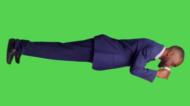 Dikey video: Ofis takım elbiseli şirket yöneticisinin profili kahve fincanı servis ediyor, kafein içeceği tutuyor ve yeşil ekranda poz veriyor. Genç işadamı sıcak bir içecek içiyor.