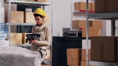 Kadın ve erkek depodaki malları tarıyor, dijital tablet ve tarayıcı kullanarak barkodları tarıyor ve ürünleri envanterde arıyor. Stok lojistiği ve sanayi hizmeti planlayan bir grup işçi.