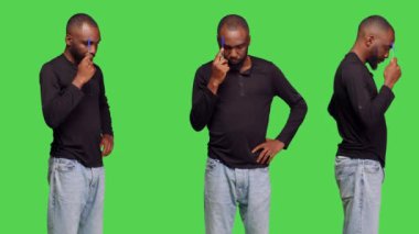 Erkek model, yeşil ekran üzerinde düşünceli davranıp kamerada yeni bilgiler bulmaya çalışıyor. Stüdyoda yenilikçi fikirler üreten, kot pantolonlu, kendine güvenen genç bir adam..