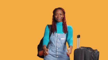 Afrika kökenli Amerikalı gezgin kameraya başparmak işareti yaparak stüdyoda başarı ve onay ifadesinde bulundu. Genç bayan turist, tatil gezisine çıkan olumlu kişi..