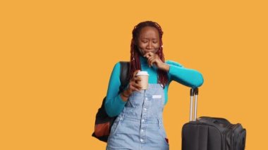 Yorgun bir kadın kahve fincanı içiyor ve kamera karşısında esniyor, uçakla tatile çıkmaya hazırlanıyor. Tatilde seyahat etmekten yorgun düşmüş, kafein içen bir kadın..