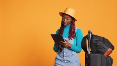 Afro-Amerikalı gezgin, tablet kullanıyor, tatildeyken dijital cihazda internet sitesine göz atıyor. Cihazda internet haritası kullanan neşeli bir kadın, yurt dışında şehir macerası.