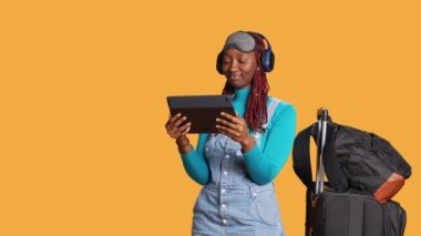 Modern insan stüdyoda tablette televizyon programı izliyor, kulaklık kullanarak uçak uçuşu sırasında televizyon dizilerinin çevrimiçi bölümlerini izliyor. Tatile gelmeden önce sinemaya bakan genç turist..