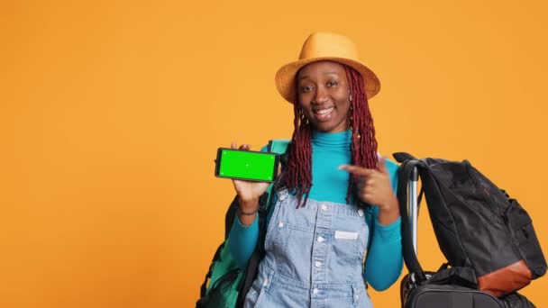 スマートフォンの緑の画面を使っている女性旅行者 カメラのクロマキーで隔離されたディスプレイを宣伝しています 携帯電話を示す笑顔の人とともに空白のモックアップコピースペーステンプレート — ストック動画