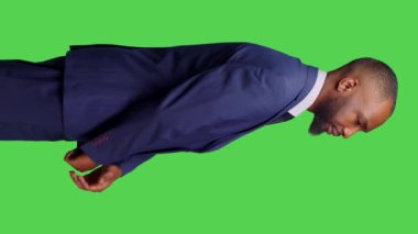 Dikey video: Afro-Amerikan işçilerin profili kamera önünde şık bir takım elbise giyip yeşil ekran arka planında poz vermeleri. İş dünyasında şirket yöneticisi olarak çalışan genç adam, iyimser erkek.