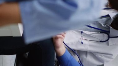 Dikey video: Hastane bekleme odasında sağlık kontrolü sırasında glukometre kullanan yaşlı bir hastanın insülin ve glikoz seviyesini ölçen doktor. Afrikalı Amerikalı doktor tıbbi test yapıyor.