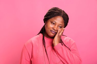 Dişlerinin ağrıması ya da diş hastalığından dolayı elleri ve ağızları birbirine değen Afrika kökenli bir manken. Stüdyoda arka planda poz verirken kadın acı çekiyor.