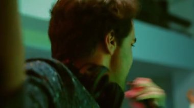 Kulüpte erkek DJ kayıt videosu, sahnede elektronik müzik ile ses istasyonunu karıştırıyor. Genç adam dans pistindeki neşeli insanlar için eğlenceli ritimler yaratıyor, parti yapıyor. El kamerasıyla..