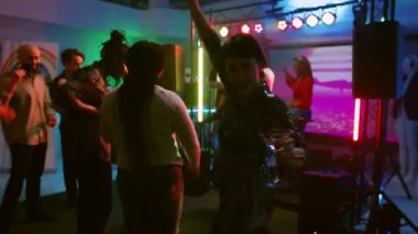 Dans pistinde arkadaşlarıyla dans eden, geceleri eğlenen ve içki içen bir kadın. Neşeli kız gece kulübünde ya da diskotekte farklı insanlarla parti yapıyor. El kamerasıyla..