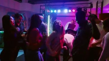 Etrafta dans eden, kulüpte mutlu hisseden disko ışıkları ve canlı gösterisiyle modern partinin tadını çıkaran eğlenceli insanların görüntüsü. Bir grup insan gece kulübünde parti veriyor, dans pistine çıkıyorlar. El kamerasıyla..