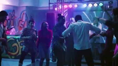 Disko partisinde canlı müzikle dans eden bir grup arkadaş, kutlama etkinliğinde doğaçlama break dans savaşıyla eğleniyorlar. Gülümseyen insanlar dans pistinde zıplıyor, parti yapıyorlar. El kamerasıyla..