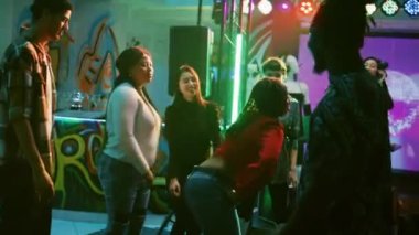 Bir grup arkadaş dans pistinde parti yapıyorlar, gece kulübünde canlı müzik dinliyorlar. Genç erkekler ve kadınlar diskotekte, dans ve zıplamada mutlu hissediyorlar. El kamerasıyla..