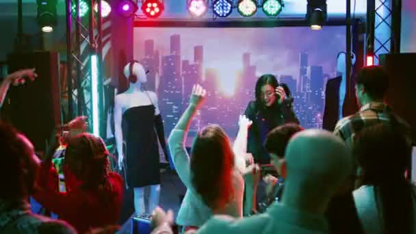 ナイトクラブステージで楽しんでいる女性Djは ダンスフロアでファンキーなクラブ雰囲気を作り出します お祝いイベントのためにディスコパーティーで電子音楽を混合若い女性 手持ち撮影 — ストック動画