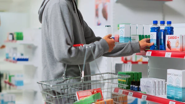 年轻人从药店的货架上取药 把医疗产品放进篮子里去买处方药 亚洲客户在药店查看维生素和补充剂盒 — 图库照片