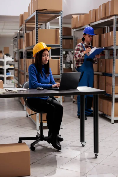 亚洲仓库员工在笔记本电脑上进行商品供应链管理 在计算机上分析客户订单清单的黄帽物流和分销操作员 — 图库照片