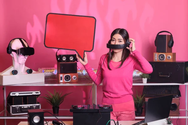 微笑的艺术家拿着红色的语音泡沫 在粉红背景的工作室里用硬纸板做广告短信 亚洲音乐家在专业的混音器控制台上演奏曲调 — 图库照片