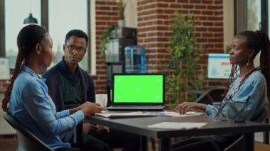 Birlikte çalışma alanında yeşil ekranlı dizüstü bilgisayar kullanan işçiler, ofiste yeni iş vizyonunu tartışmak için toplanıyorlar. Şirket analistleri krom anahtar telif uzayı ile izole edilmiş görüntüyü inceliyorlar. Üçayak atışı.