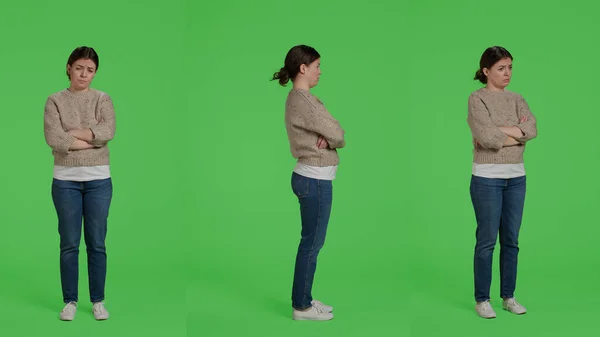 Displeased person acting sad and discouraged posing over isolated greenscreen backdrop, being disappointed and depressed. Young upset adult standing over full body studio background.