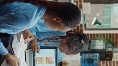 Dikey video: Analiz planlaması yapan işçiler ekibi, ortak çalışma alanında iş birliği üzerinde çalışıyor. Şirket çalışanları, ajans ofisinde yeni strateji ve vizyonu tartışmak için toplanıyor..