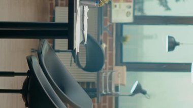 Dikey video: Boş iş ofisindeki yönetim kurulu masası, bilgisayar ve belgelerle dolu ajans ortak çalışma alanı. Başlangıç işleri ve projeleri için çalışma istasyonları olan küresel bölüm merkezi.