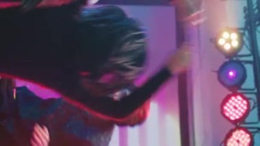 Dikey video: Farklı insanlar dans müziğine atlıyor, diskotekte dans pistinde neşeli hissediyorlar. Modern müzik eşliğinde dans eden bir grup arkadaş sahnede DJ 'lik yapıyor, birlikte kulüpler kuruyorlar. Üçayak atışı.