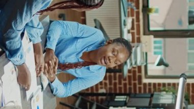 Dikey video: Kağıtlar üzerinde istatistiklerle birlikte araştırma projesi üzerinde çalışan meslektaşlar, yürütme analitik planı hakkında tartışıyorlar. Yönetim ekibi kurul toplantısında raporları inceliyor, ortak çalışma alanı.