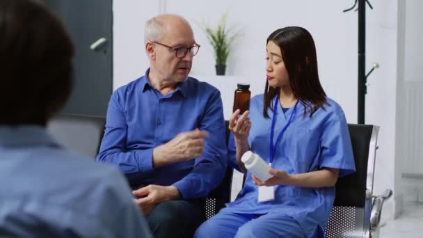 Asiatische Krankenschwester Zeigt Älteren Patienten Die Tablettenflasche Und Bespricht Die — Stockvideo
