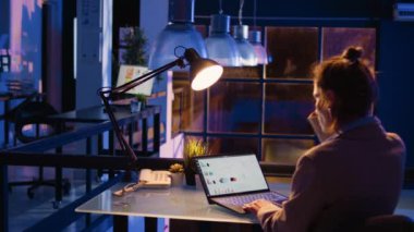 Girişimci, finansal veri raporlarını gece geç saatlerde diyagramlarla kontrol ederek kârın artmasına yardımcı oluyor. İstatistiklerle ekonomi yatırımı üzerine çalışan kadın girişimci. El kamerasıyla..