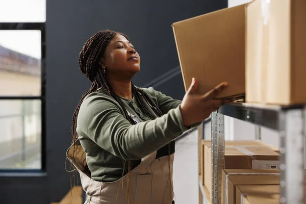 非裔美国人把纸板箱放在金属货架上 为客户准备仓库订单 库房员工在商品库存工作 进行产品质量控制 — 图库照片